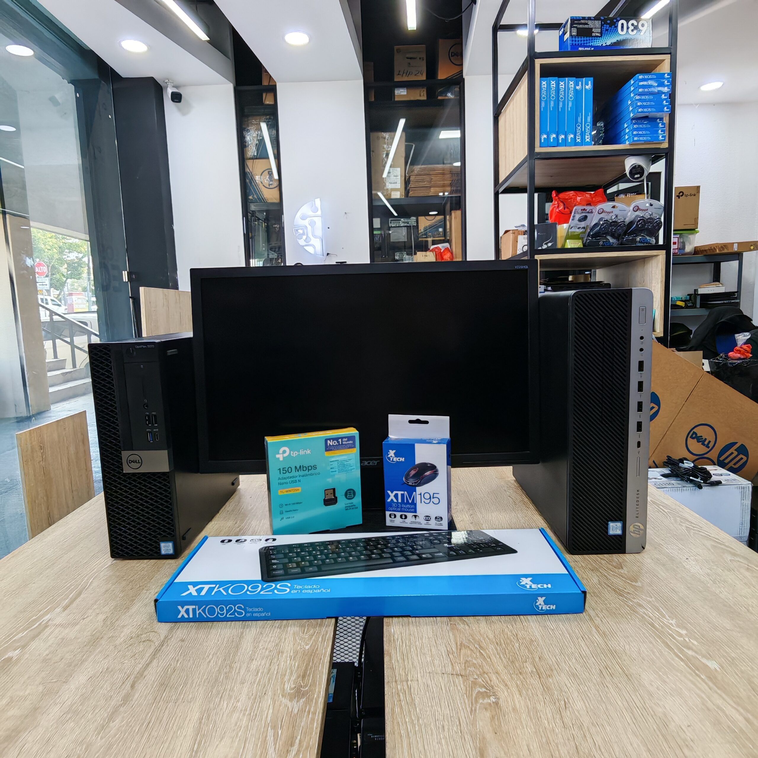 Imagen publicitaria de Compusdeguate en Novicentro Zona 5, mostrando dos computadoras de escritorio, una marca Dell y otra HP, junto a un monitor de 22 pulgadas. El encabezado pregunta '¿HP o Dell?' y detalla especificaciones: Core i5 8va gen, 8GB Ram, 240gb SSD por un precio de Q3,365.00. En frente se muestran sus accesorios: teclado Xtech, mouse óptico y adaptador Wifi TP-Link sobre un escritorio de madera clara