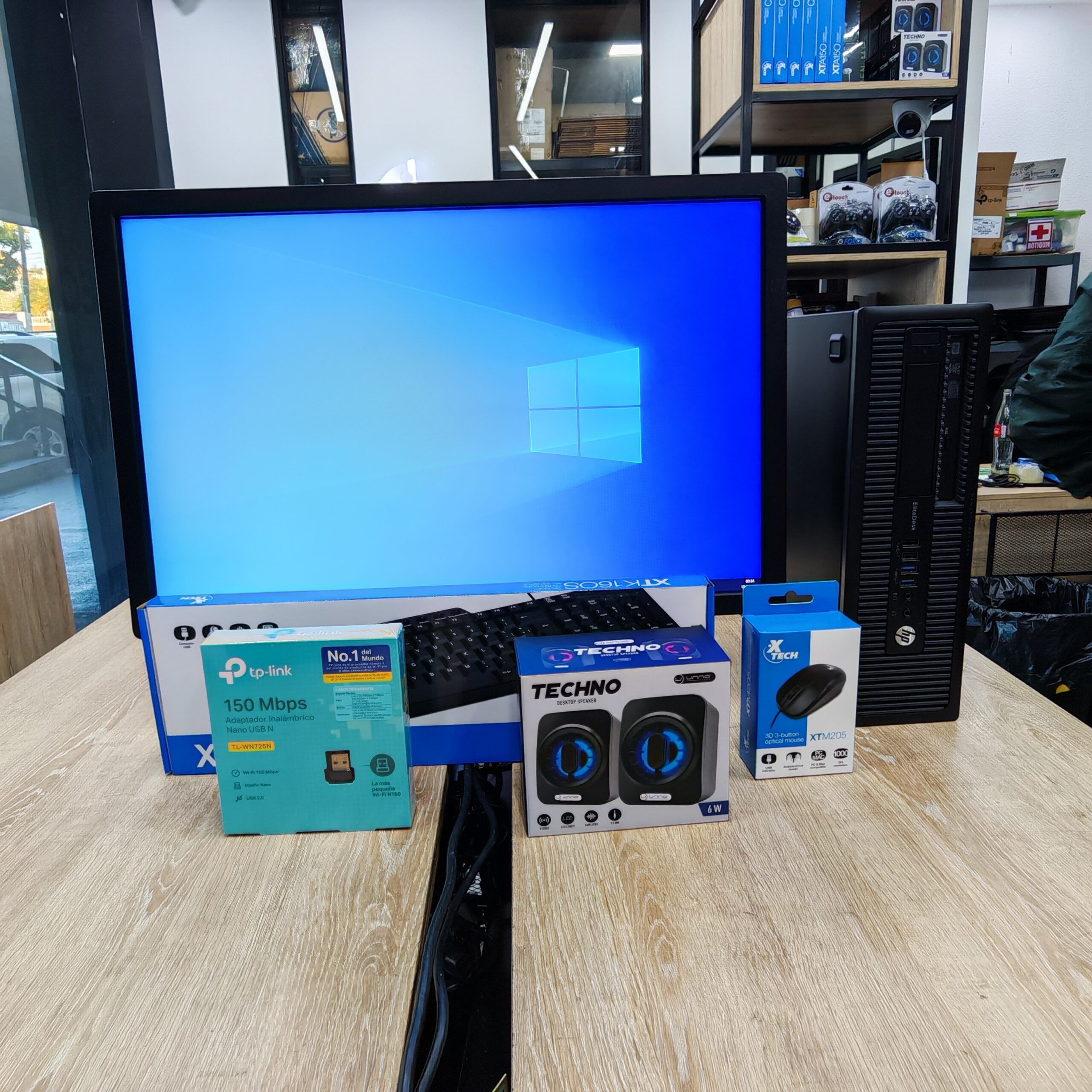 Combo de computadora profesional HP EliteDesk en Compusdeguate, Centro Comercial Novicentro. La pantalla de 22 pulgadas muestra un fondo de Windows 10 y las especificaciones: Core i7 de 6ta generación, 16GB de RAM, 240GB SSD más 1TB de disco duro. En primer plano se observan accesorios incluidos: bocinas Techno, adaptador Wifi TP-Link, teclado y mouse Xtech. Imagen profesional que resalta potencia y capacidad de almacenamiento.